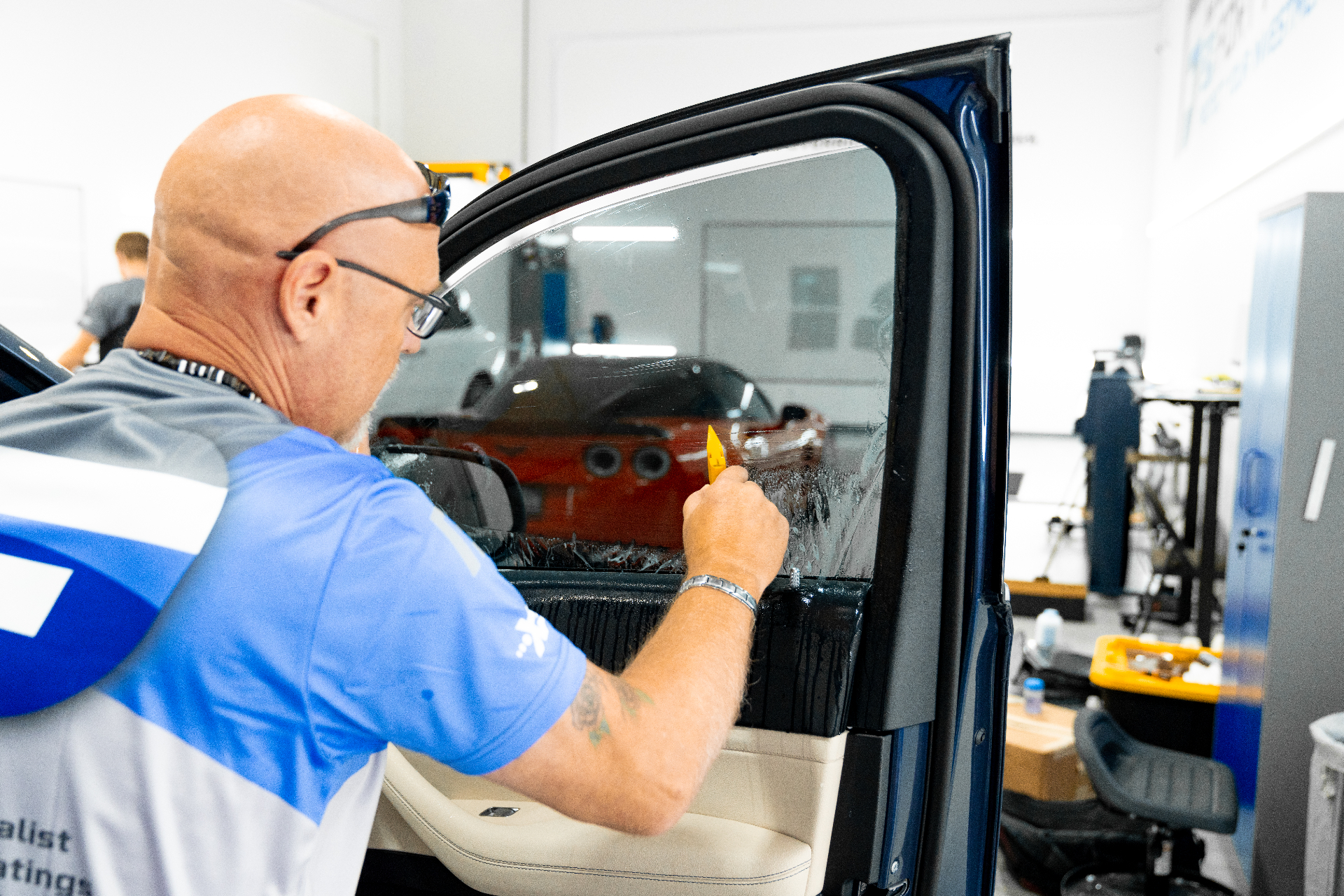 XPEL installer applying ceramic window tint to a rear quarter glass panel